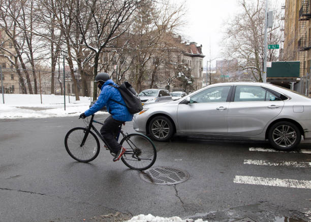 Cyclist passing parked cars on a Skien street during commute hours